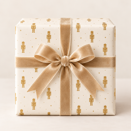 Maison Velere Ivory and Gold Nutcracker wrapping paper on a wrapped gift with champagne-gold ribbon